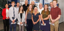 Twelve people pose together in front of a wall at WMUR TV